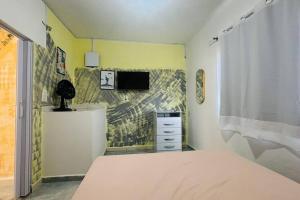 a bedroom with a bed and a tv on a wall at Kitnet Mobiliada itapua Vila Velha in Vila Velha