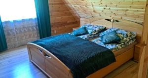 a bed in a room with a wooden wall at Domek Sauna Gaładuś in Radziucie