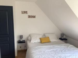 a bedroom with a white bed with a yellow pillow at Le petit Four Neuf in Lézardrieux +13 photos
