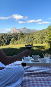 a person holding a glass of wine on a table at Chalés Peterli 2 in Venda Nova do Imigrante