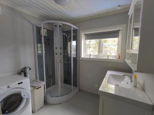 a bathroom with a shower and a sink and a washing machine at Hytte ved Vråvatnet i Vrådal in Sinnes