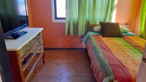 a small bedroom with a bed and a television at Alojamiento Placilla - San Antonio in San Antonio