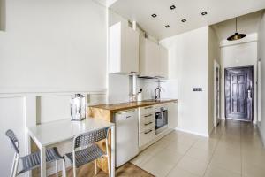 a kitchen with white cabinets and a table and chairs at Studio Marszałkowska in Warsaw