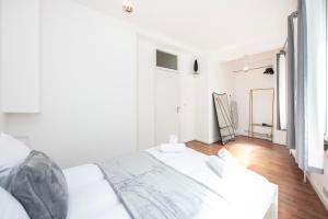 ein weißes Schlafzimmer mit einem großen weißen Bett und Holzböden in der Unterkunft Spacious 1 BR Near London Bridge - 5 Min Walk in London