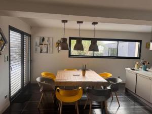 Jolie maison avec piscine et Spa في La Guerche-de-Bretagne: غرفة طعام مع طاولة خشبية وكراسي صفراء