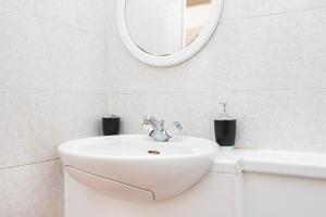 ein weißes Badezimmer mit einem Waschbecken und einem Spiegel in der Unterkunft Spacious 1 BR Near London Bridge - 5 Min Walk in London