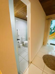 a room with a bathroom with a toilet and a doorway at Pousada Coco Dendê in Ilha de Boipeba