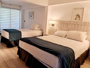 a bedroom with two beds and a window at Hotel Palmas de La Serena in La Serena