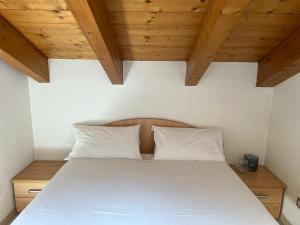 a bedroom with a white bed with wooden ceilings at La Valle Maggiore in Villa di Tirano
