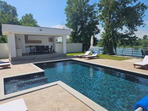 a swimming pool with two chairs and a house at Drina Lux in Loznica