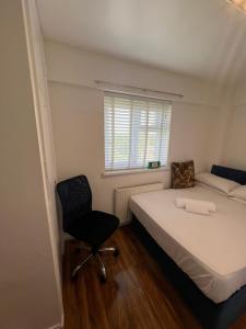um quarto com uma cama, uma cadeira e uma janela em Stylish London double room em Londres