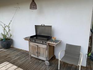 einem Grill auf einem Holztisch neben einem Stuhl in der Unterkunft une maison lumineuse sous les pins in Le Canon