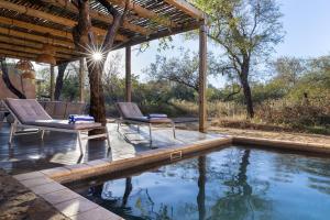 um pátio com 2 cadeiras e uma piscina em Rixile Kruger Lodge em Skukuza