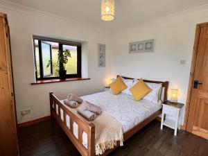 a bedroom with a bed with yellow pillows and a window at Detached 3 Bed Cottage Mountain Views- Pets Wifi in Beaumaris