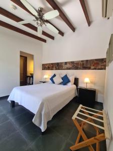 a bedroom with a white bed and a ceiling fan at Posada El Capullo in Colonia del Sacramento