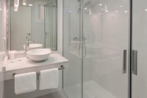 uma casa de banho branca com um lavatório e um chuveiro em Hotel Jucamar em Cangas