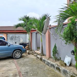 ein Auto parkt auf einem Parkplatz neben einem Haus in der Unterkunft Hotel De Pisces in Uyo
