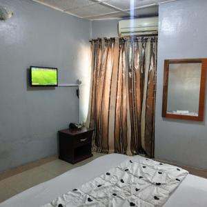 ein Schlafzimmer mit einem Bett und einem TV an der Wand in der Unterkunft Hotel De Pisces in Uyo