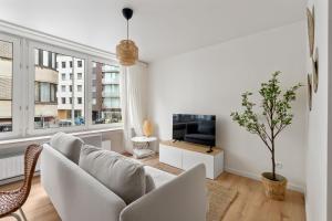 a white living room with a couch and a tv at Studio Petite Plage in Ostend