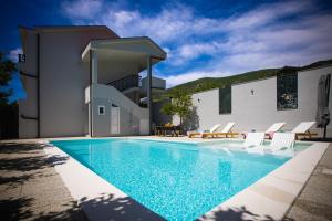 a swimming pool with chairs and a house at Villa Flumen, Private Pool, Family Villa in Mostar