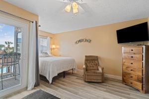 1 dormitorio con 1 cama, TV y silla en GS Plantation West 1264 by Vacation Homes Collection, en Gulf Highlands