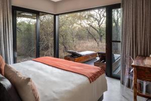 a bedroom with a bed and a large window at Rixile Kruger Lodge in Skukuza