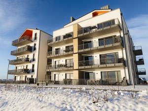 un immeuble d'appartements avec de la neige devant lui dans l'établissement Hygge Lodge 18 Meerblick am Strand, à Olpenitz