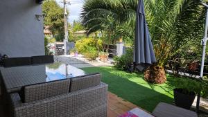 an outdoor patio with an umbrella and a lawn at VILLA Zaphira in Gujan-Mestras