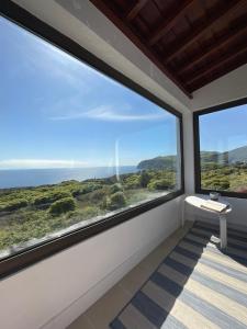 a room with large windows looking out at the ocean at Casa do Padre in Santa Cruz da Graciosa