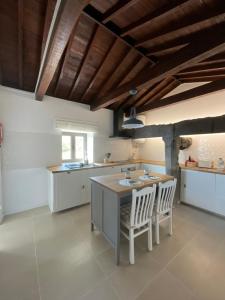 a kitchen with white cabinets and a table and chairs at Casa do Padre in Santa Cruz da Graciosa
