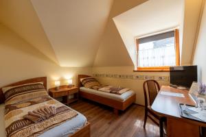 um quarto com uma cama, uma secretária e uma janela em Szenti Vendégház em Győr