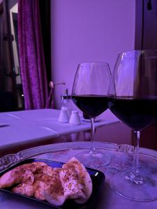 カランバカにあるEpavlis Meteora Suites Hotelのワイン2杯、テーブルの上に盛り付けられた料理