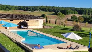a swimming pool with two umbrellas and a house at Les Bouges in Salles