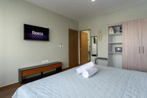 1 dormitorio con 1 cama y TV en la pared en NewComfy~5 Area~Walk 2 Beach~Pool~Views~King Bed, en Mazatlán