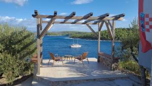 a patio with a table and chairs and a boat in the water at PERFECT NEST at Sunset Beach in Vela Luka