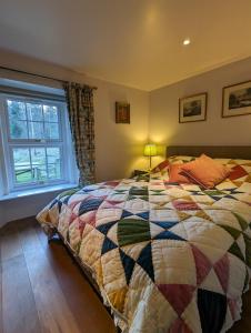 a bedroom with a bed with a colorful quilt at Birkenside Cottage in Jedburgh