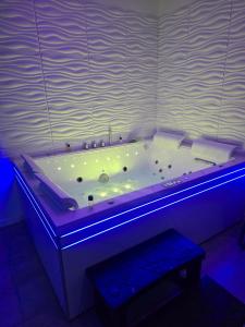 Maison équipée - balnéothérapie - sauna infrarouge - siège massant et pièce secrète : حوض استحمام كبير مع ضوء أزرق في الغرفة