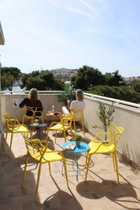 deux femmes assises sur un balcon avec des chaises et des tables jaunes dans l'établissement Hostel Petra Marina, à Dubrovnik