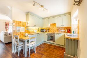 a kitchen with white cabinets and a table with chairs at Gingerbread Cottage in Hawkshead