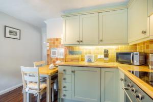 a kitchen with green cabinets and a table and a microwave at Gingerbread Cottage in Hawkshead