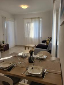 a dining room table with plates and wine glasses at Apartments A&A in Biograd na Moru