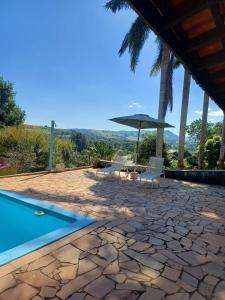 un patio avec une table, des chaises et un parasol dans l'établissement Recanto da Tuca, à Socorro