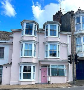 una casa rosa con una puerta rosa en una calle en One Sandringham - Boutique Seaside Home in Ilfracombe, en Ilfracombe