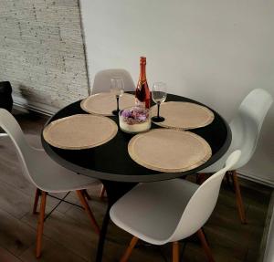 - une table avec 4 chaises et une bouteille de vin dans l'établissement APARTAMENT PRZY WYSPIE, à Darłowo