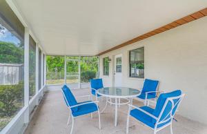 a porch with a glass table and blue chairs at 13 Mi to Hudson Beach Spring Hill Home with Lanai in Spring Hill