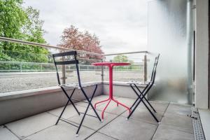 Aurora Suite à Champel avec terrasse في جنيف: كرسيين وطاولة حمراء على شرفة