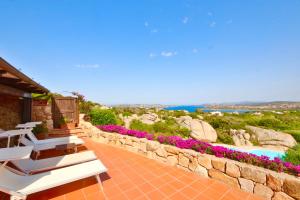 a patio with white chairs and a stone wall at Cottage Sardinia by KlabHouse in Palau