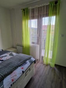 Schlafzimmer mit grünen Vorhängen und einem Bett mit Fenster in der Unterkunft Sobe Lejla in Vipava