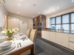 uma cozinha com armários brancos e uma mesa e cadeiras em Mayfair - Exclusive 4 Bedroom Apartment em Londres