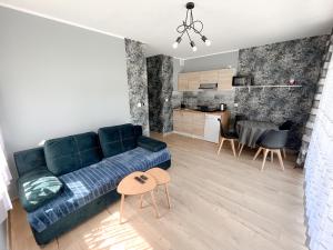a living room with a blue couch and a kitchen at Grądzka Dolinka in Grądzkie